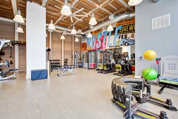 A gym with weights and cardio equipment on the floor and a wall with a banner